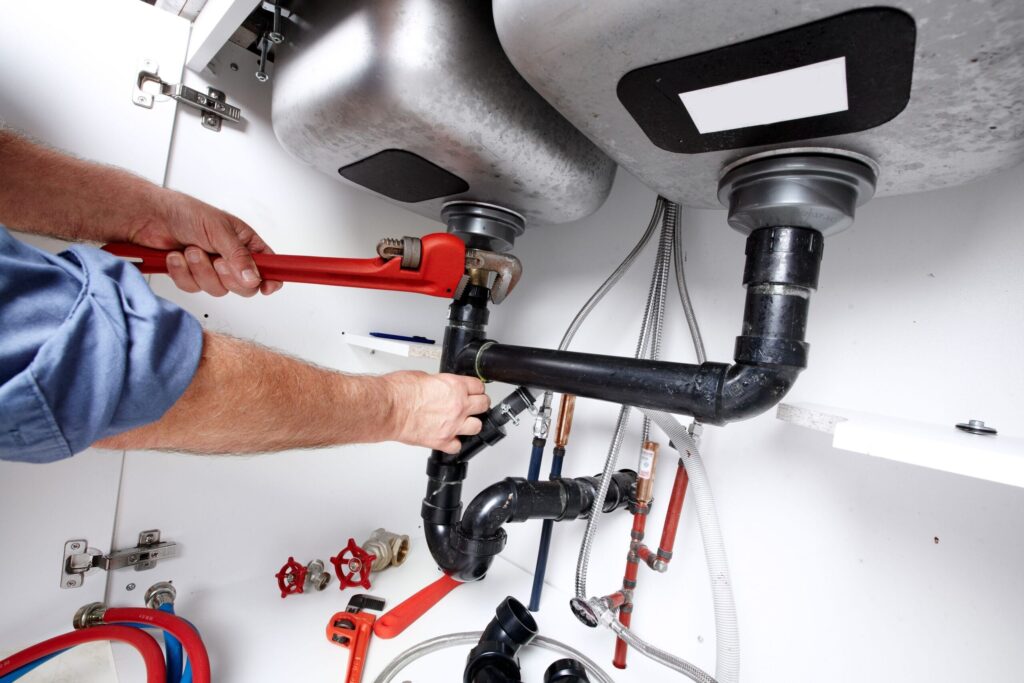 Plumber repairing drain pipes beneath a kitchen sink in Silver Spring